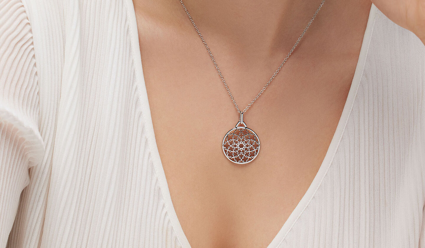 A woman wearing a Birks Muse silver medallion necklace.